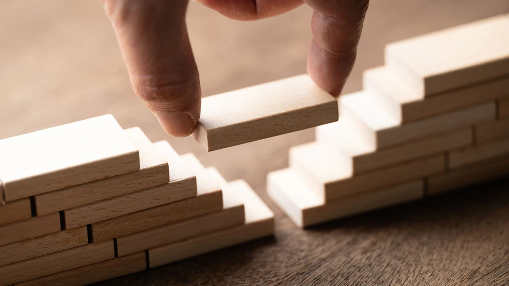 Nell’immagine è raffigurata una mano che dispone dei blocchetti di legno in modo da creare uno spazio vuoto tra due strutture a gradini.
